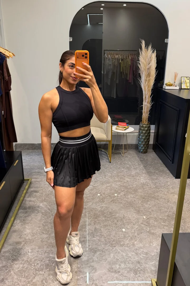 Look preto com top cropped e saia, fotografado no espelho da loja