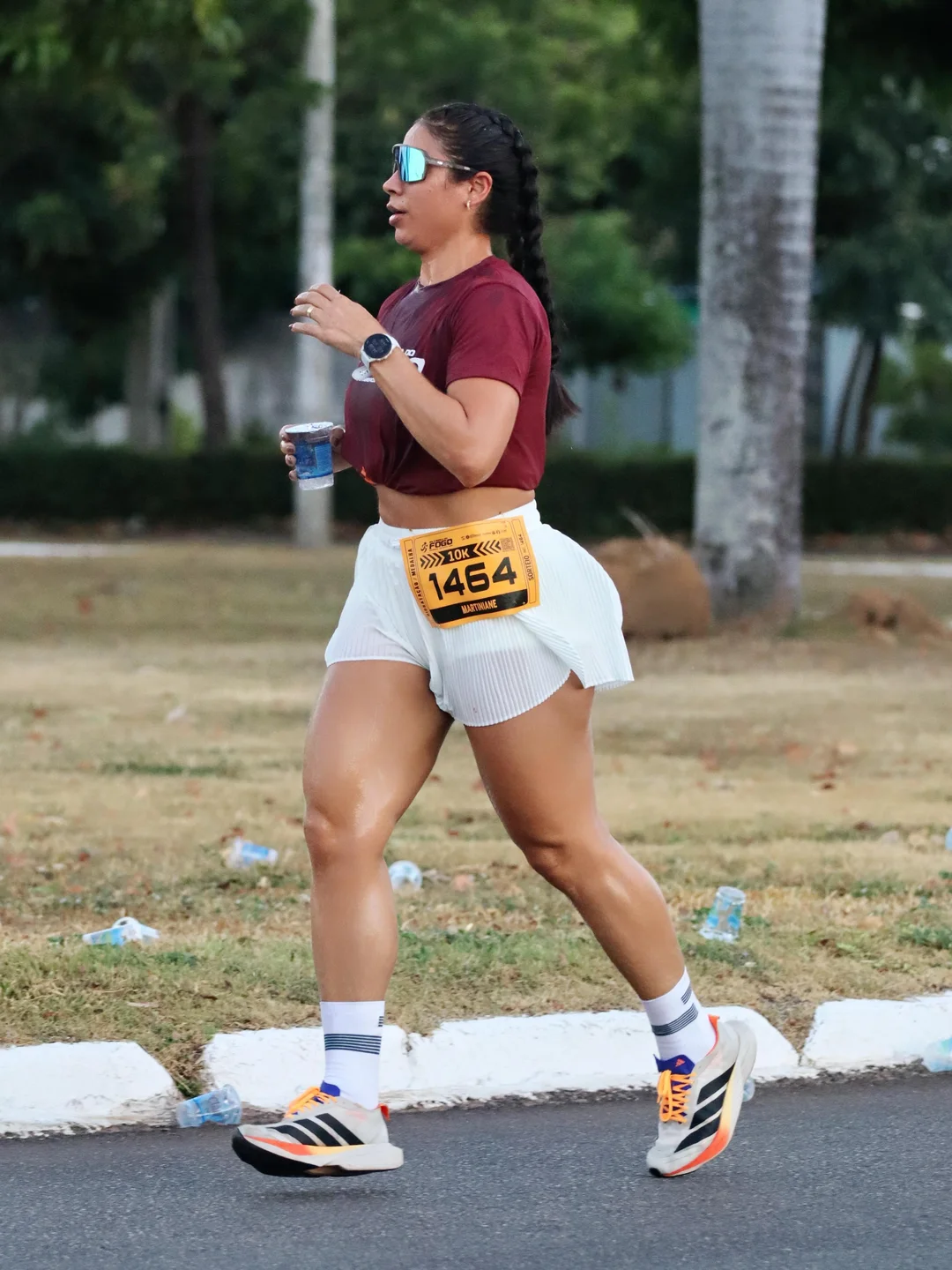 Corredora de short branco plissado e número de peito em prova de rua